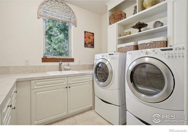 washroom with a sink, light tile patterned flooring, cabinet space, and washing machine and dryer