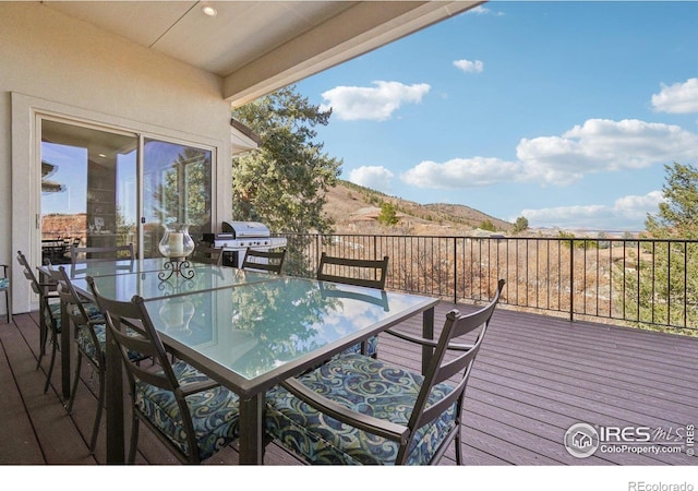wooden deck with outdoor dining area, a mountain view, and grilling area