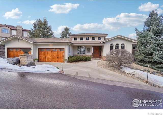 view of front of house featuring covered porch, driveway, a garage, stucco siding, and a chimney