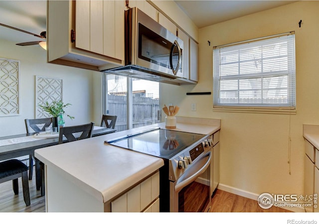1865 Terry St Unit 3, Longmont, CO 80501 - kitchen with light countertops, light wood-type flooring, baseboards, a ceiling fan, and appliances with stainless steel finishes