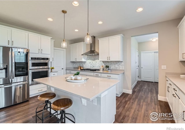 38 Morgan Cir S, Erie, CO 80516 - kitchen featuring appliances with stainless steel finishes, wall chimney exhaust hood, a center island, white cabinetry, and recessed lighting
