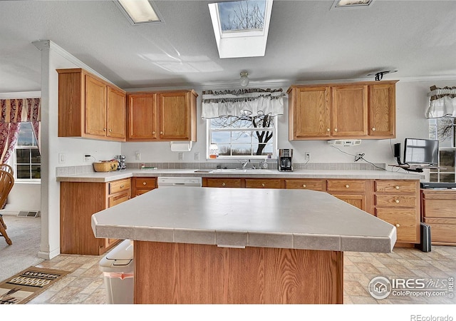 24505 County Road 53, Kersey, CO 80644 - kitchen with light countertops, crown molding, a center island, light stone finish flooring, and brown cabinets