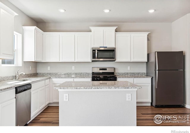 974 Cascade Falls St, Severance, CO 80550 - kitchen featuring stainless steel appliances, a center island, white cabinets, dark wood finished floors, and light stone counters