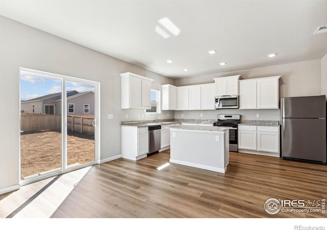 974 Cascade Falls St, Severance, CO 80550 - kitchen featuring stainless steel appliances, wood finished floors, white cabinets, recessed lighting, and a center island