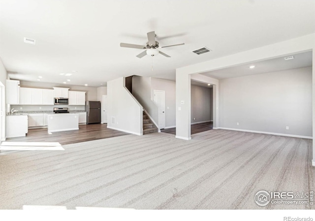 974 Cascade Falls St, Severance, CO 80550 - unfurnished living room with carpet flooring, recessed lighting, a ceiling fan, and stairs