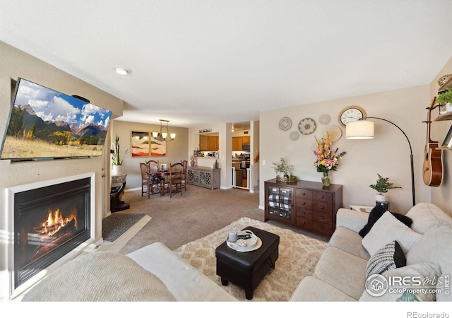 living area with an inviting chandelier, carpet flooring, and a glass covered fireplace