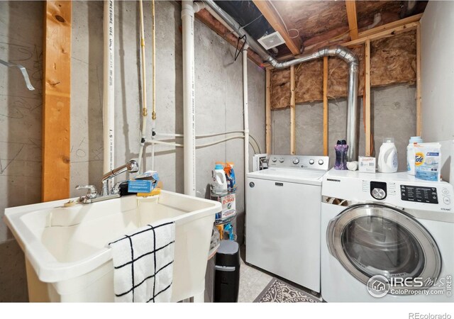 clothes washing area featuring independent washer and dryer, laundry area, and a sink