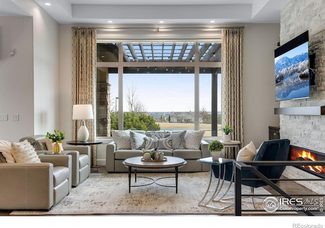 living area featuring a stone fireplace and recessed lighting