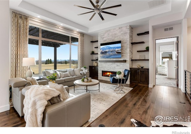 living area with dark wood-style floors, a tray ceiling, and visible vents