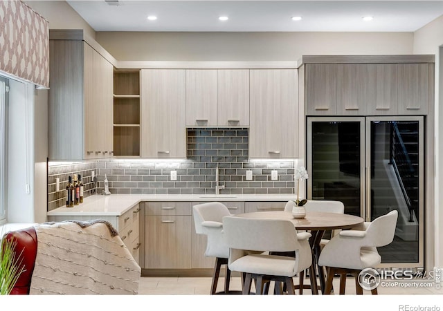 kitchen with modern cabinets, a sink, light countertops, and tasteful backsplash