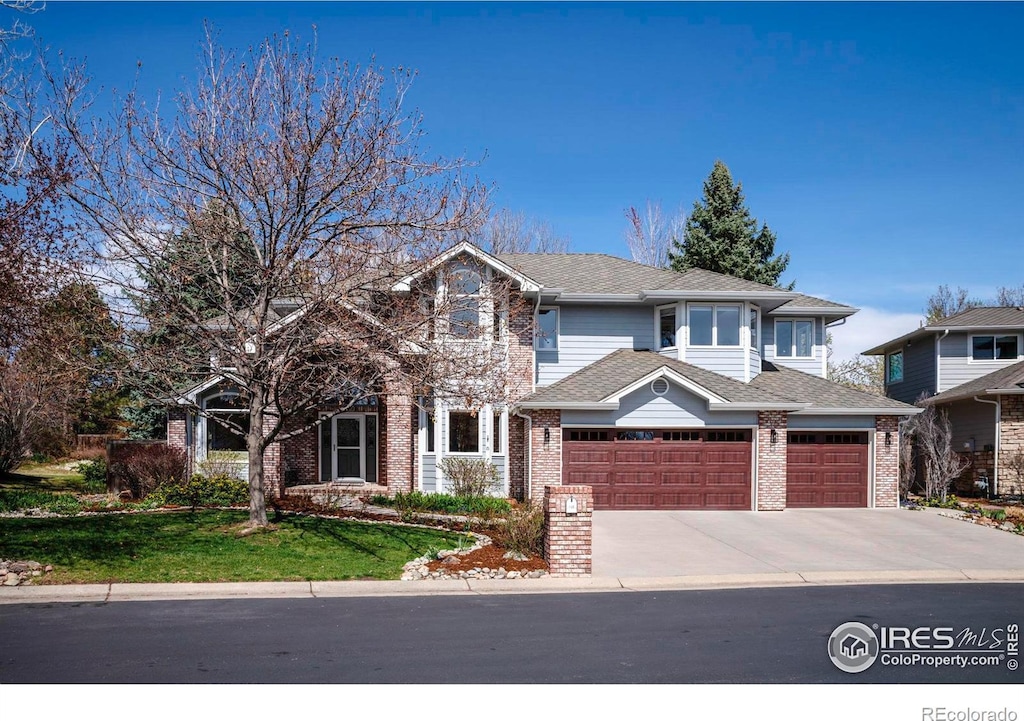 543 Manorwood Ln, Louisville, CO 80027 - traditional home with an attached garage, brick siding, and concrete driveway