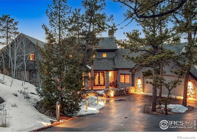 2251 Fox Acres Dr E, Red Feather Lakes, CO 80545 - view of front of property with driveway, a shingled roof, a chimney, an attached garage, and stone siding
