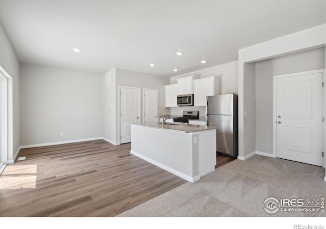 kitchen with stainless steel appliances, a kitchen island with sink, baseboards, white cabinets, and recessed lighting