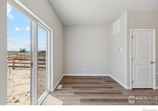 empty room with baseboards, visible vents, and wood finished floors