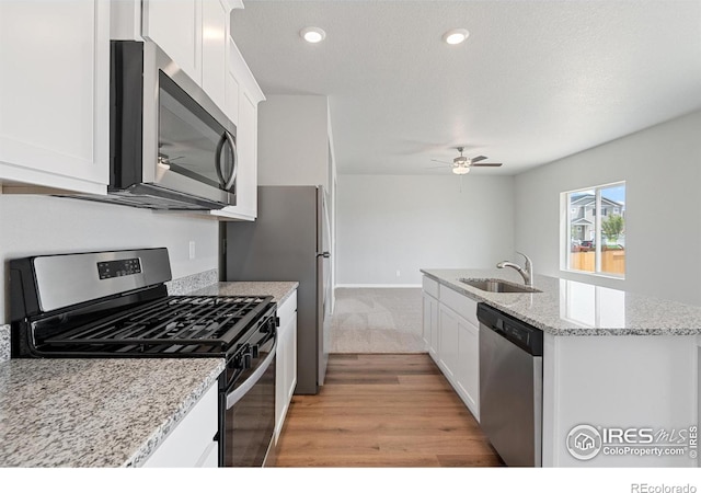 kitchen featuring ceiling fan, a sink, stainless steel appliances, and white cabinets