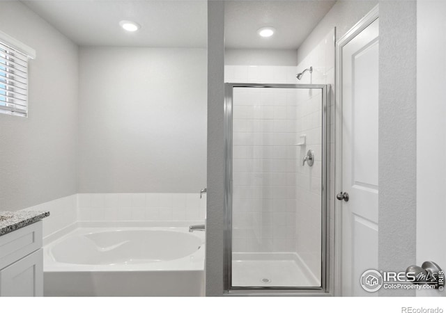 bathroom featuring vanity, a bath, and a shower stall