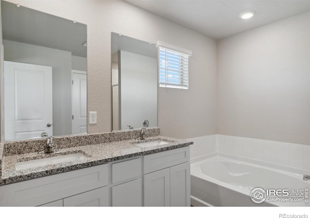 full bath with double vanity, a sink, and a bath