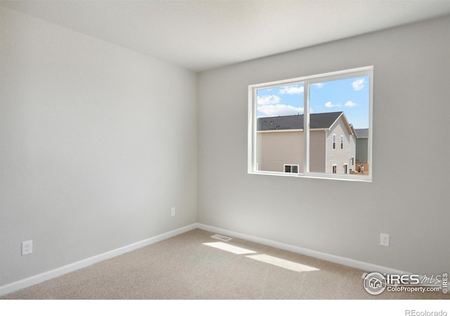 carpeted empty room featuring baseboards and visible vents