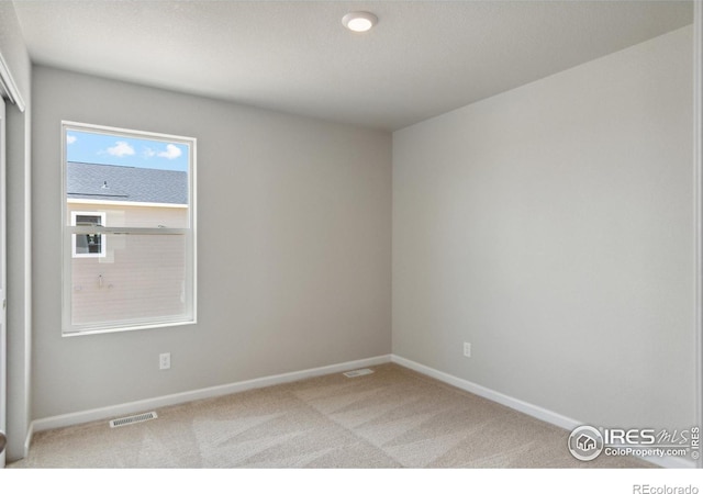 empty room with carpet, baseboards, and visible vents