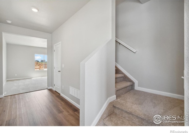 staircase featuring baseboards, visible vents, wood finished floors, and carpet flooring