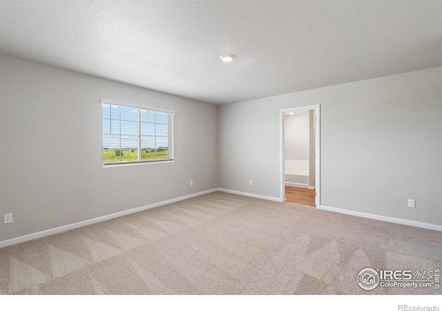 unfurnished room featuring carpet floors, baseboards, and a textured ceiling