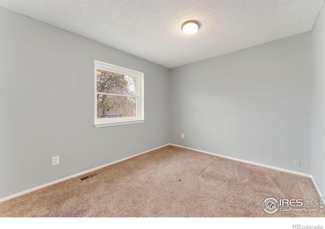 unfurnished room featuring a textured ceiling, baseboards, carpet, and visible vents