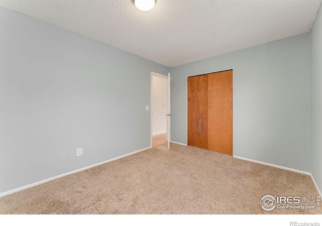 unfurnished bedroom with a closet, baseboards, carpet flooring, and a textured ceiling