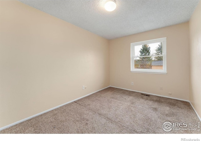 carpeted spare room featuring visible vents, baseboards, and a textured ceiling