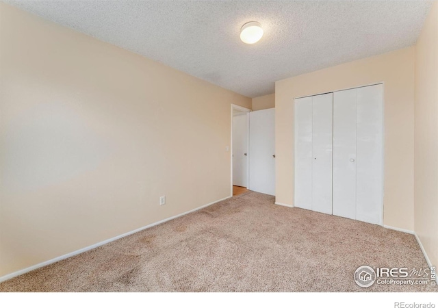 unfurnished bedroom featuring a textured ceiling, a closet, baseboards, and carpet floors