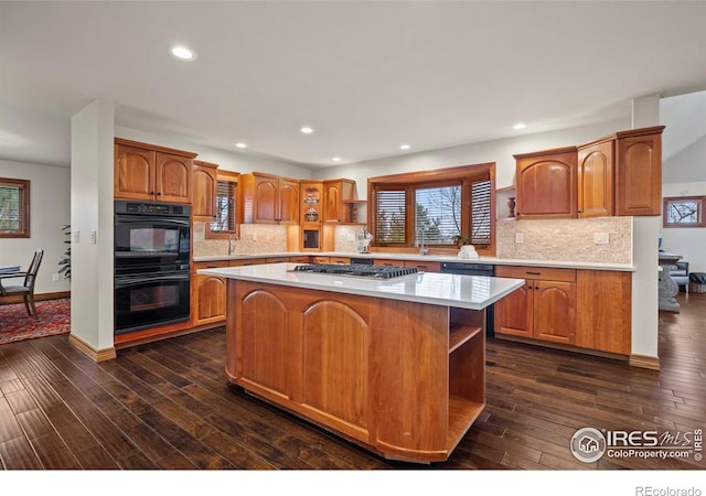 kitchen featuring dark wood-style flooring, light countertops, open shelves, black appliances, and a center island