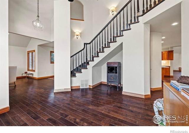interior space with a towering ceiling, baseboards, stairway, and wood finished floors