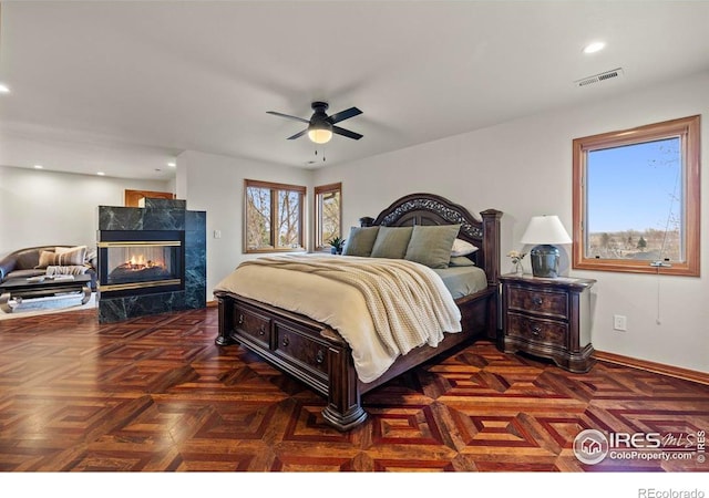 bedroom featuring a premium fireplace, recessed lighting, baseboards, ceiling fan, and visible vents