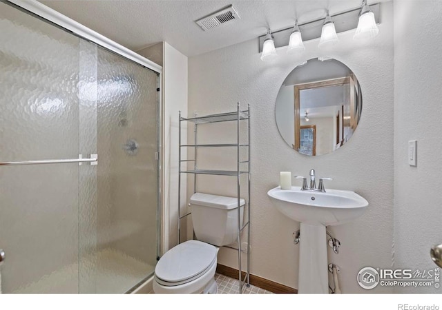 bathroom with a textured ceiling, visible vents, a shower stall, baseboards, and toilet