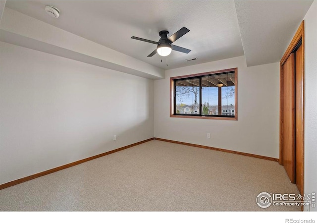 unfurnished bedroom featuring a closet, visible vents, baseboards, ceiling fan, and light colored carpet