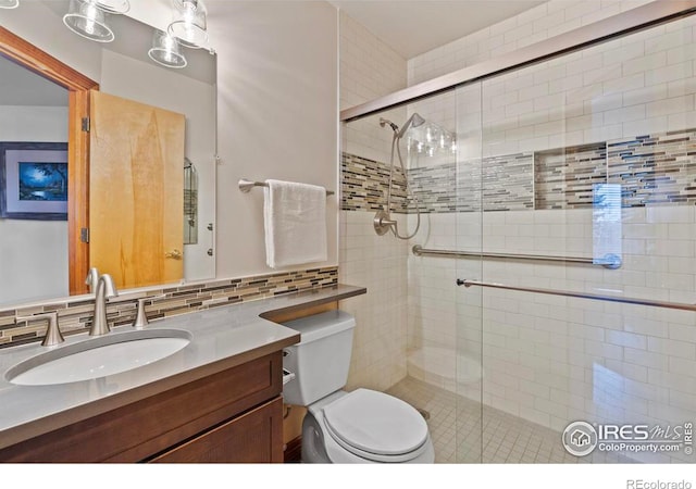 bathroom featuring a shower stall, toilet, decorative backsplash, and vanity