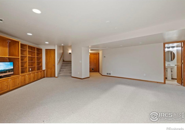 unfurnished living room featuring stairway, baseboards, light colored carpet, visible vents, and recessed lighting