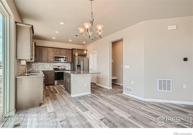 2387 Bristol St, Superior, CO 80027 - kitchen with appliances with stainless steel finishes, light wood-style flooring, a center island, decorative backsplash, and a chandelier