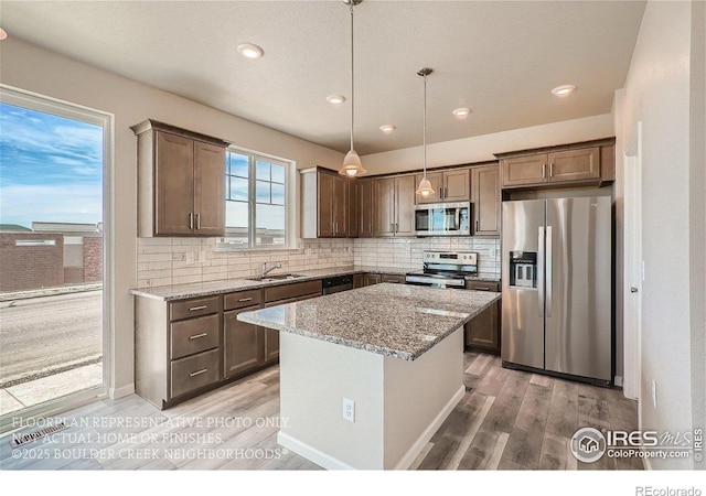 2387 Bristol St, Superior, CO 80027 - kitchen featuring appliances with stainless steel finishes, a sink, light wood finished floors, light stone countertops, and tasteful backsplash