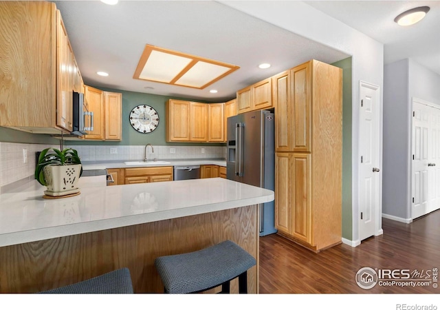 2747 Dafina Dr, Loveland, CO 80537 - kitchen featuring appliances with stainless steel finishes, tasteful backsplash, dark wood finished floors, a sink, and a peninsula
