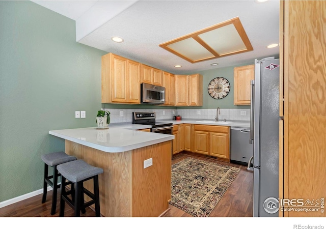 2747 Dafina Dr, Loveland, CO 80537 - kitchen with light brown cabinetry, tasteful backsplash, a sink, a peninsula, and stainless steel appliances