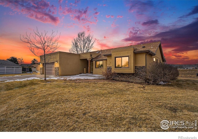 7889 Antelope Ct, Wellington, CO 80549 - view of front of property with stone siding, a front lawn, stucco siding, and an attached garage