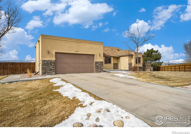 7889 Antelope Ct, Wellington, CO 80549 - view of front facade featuring stucco siding, a garage, fence, and concrete driveway