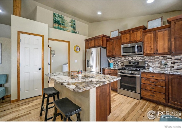 7889 Antelope Ct, Wellington, CO 80549 - kitchen featuring a kitchen bar, stainless steel appliances, light wood finished floors, and decorative backsplash