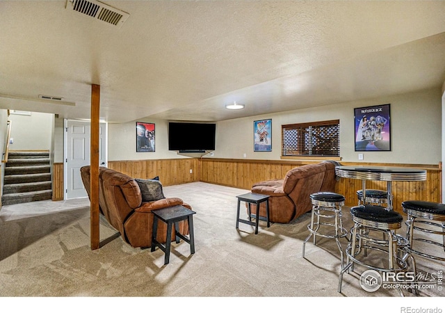 7889 Antelope Ct, Wellington, CO 80549 - living area featuring wooden walls, a textured ceiling, wainscoting, visible vents, and carpet