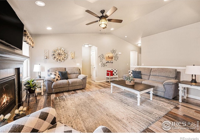 1108 Osprey Way, Wiggins, CO 80654 - living room with arched walkways, ceiling fan, wood finished floors, and a warm lit fireplace