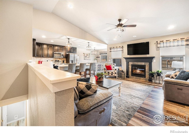 1108 Osprey Way, Wiggins, CO 80654 - living area featuring wood finished floors, recessed lighting, a ceiling fan, a glass covered fireplace, and vaulted ceiling