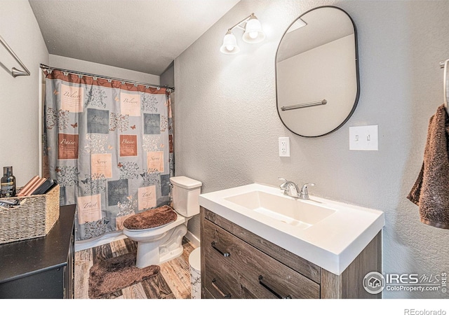 1108 Osprey Way, Wiggins, CO 80654 - bathroom featuring toilet, vanity, a textured wall, and wood finished floors