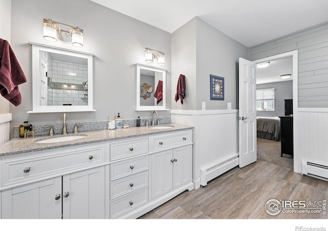 6850 Frying Pan Rd, Boulder, CO 80301 - ensuite bathroom featuring a baseboard heating unit, wood finished floors, double vanity, a baseboard radiator, and wooden walls