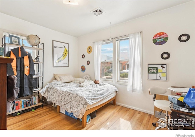 bedroom featuring baseboards, visible vents, and wood finished floors