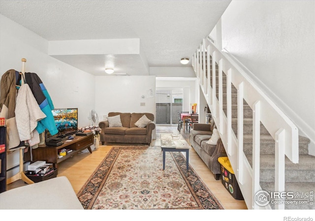 living room with stairs, a textured ceiling, and wood finished floors